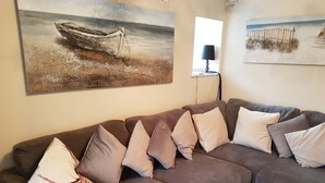 A living room with a large brown sofa, multiple cushions, and two paintings on the wall. - Eilean Donan View (Kyle)