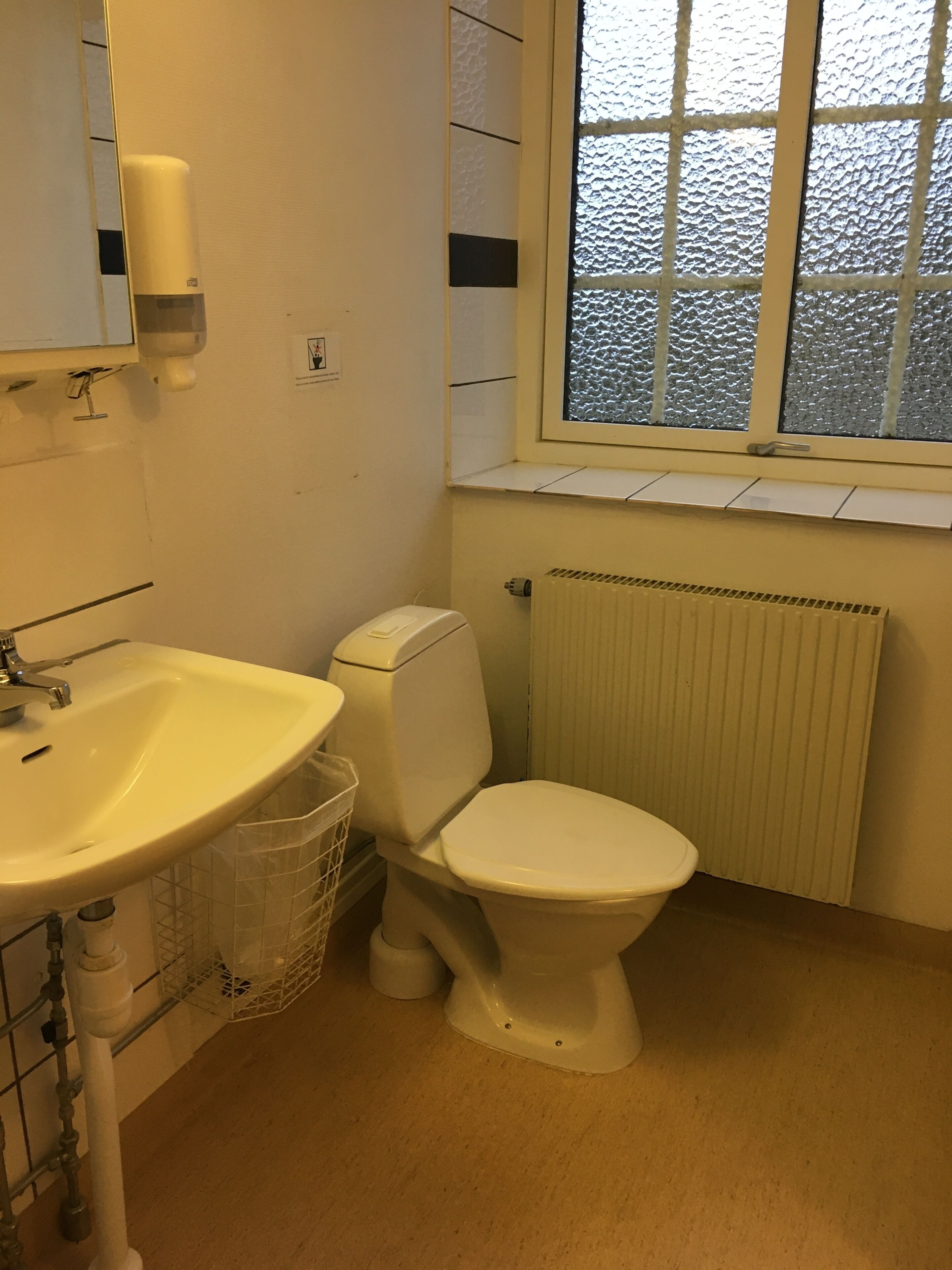 Un baño con lavamanos blanco, inodoro y ventana.