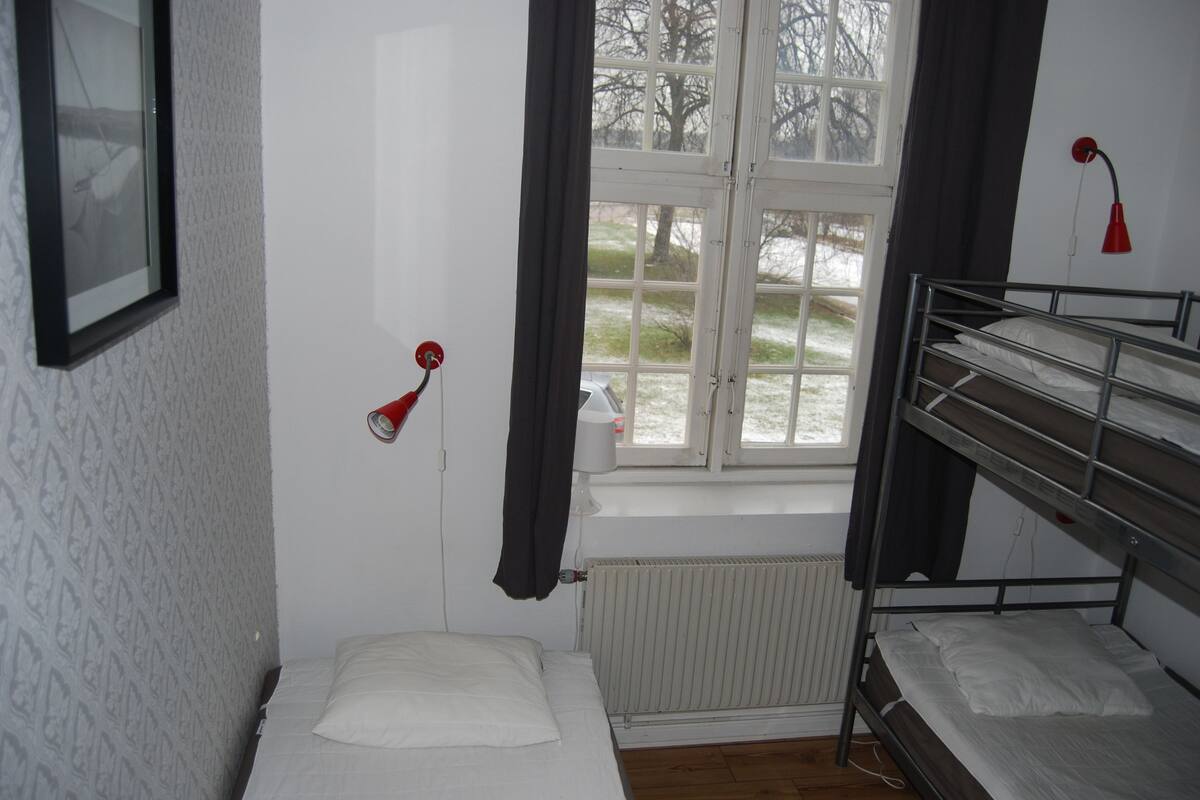 A small, single-bed room with a window, a radiator, and a bunk bed.