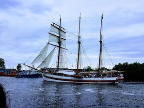 Un gran barco de vela con varios mástiles y velas amarrado en un puerto.