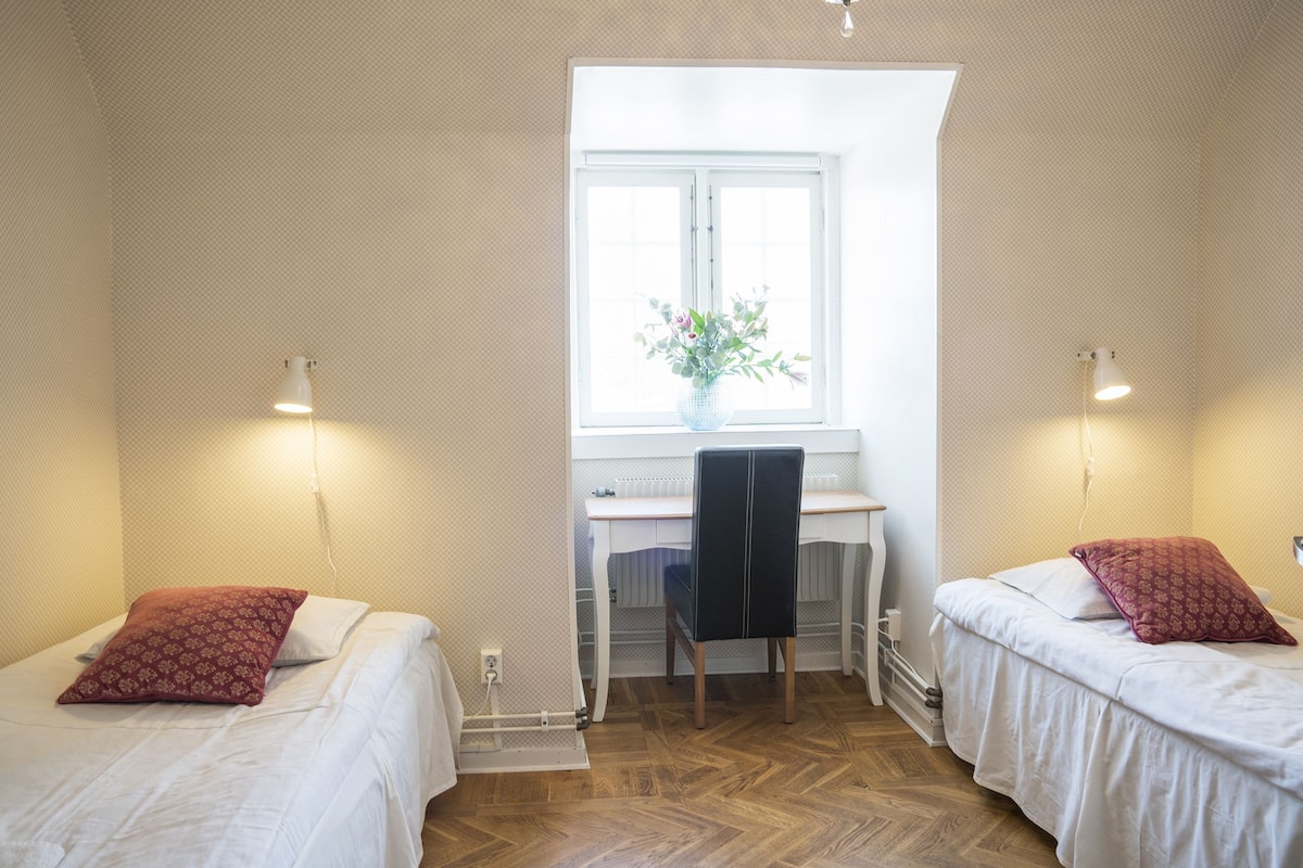 A bedroom with two beds, a desk, and a chair.