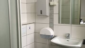 A bathroom with a toilet, a sink, a hand dryer, and a mirror.