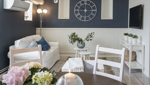Ett modernt vardagsrum med en vit soffa, ett runt bord med ett ljus och en dekorativ vas med blommor.