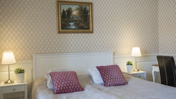 A neatly arranged bedroom with a bed, two nightstands, a chair, and a painting on the wall.