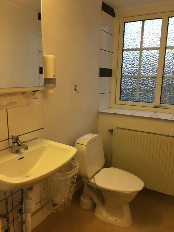 Un baño con lavamanos, inodoro y ventana.