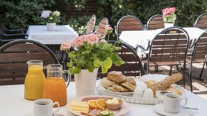En frukostuppläggning med ett varierat utbud av matvaror, inklusive bröd, ost och frukt, på ett bord täckt med ett vitt bordslinne.