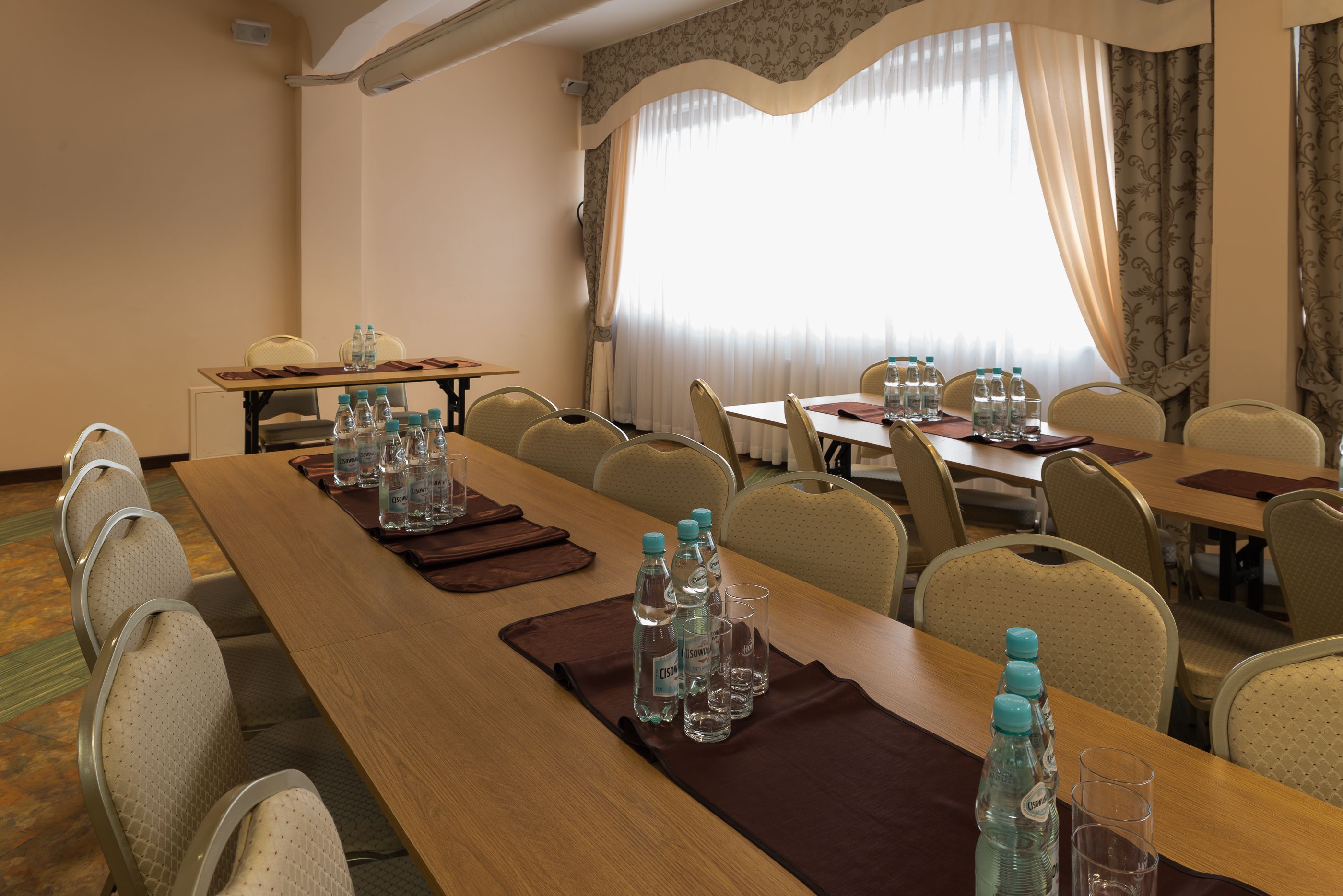 Ein Konferenzraum mit einem langen Tisch, Stühlen, Wasserflaschen und Gläsern.