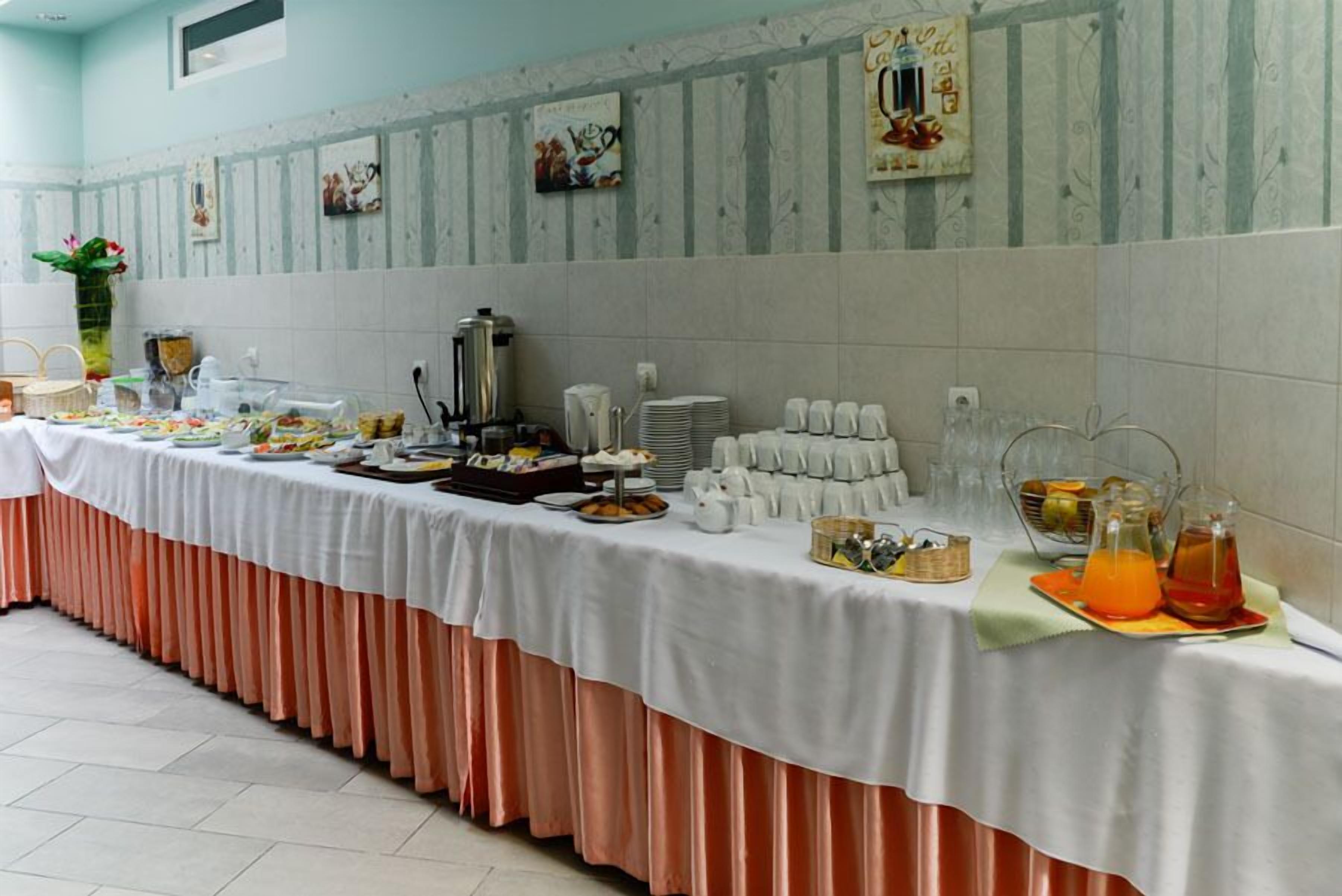A buffet setup with various food items and beverages, a coffee station, and a decorative wall with framed pictures.