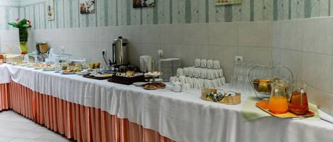 A buffet setup with various food items and beverages, a coffee station, and a decorative wall with framed pictures.