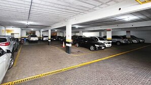 Un estacionamiento subterráneo de varios niveles con varios coches aparcados en plazas designadas.