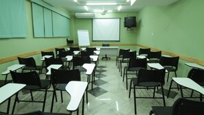 Un aula con filas de escritorios y sillas, una pizarra y una pantalla de proyector.