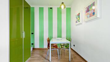 A dining area with a white table and chairs, green striped walls, and a hanging light fixture.