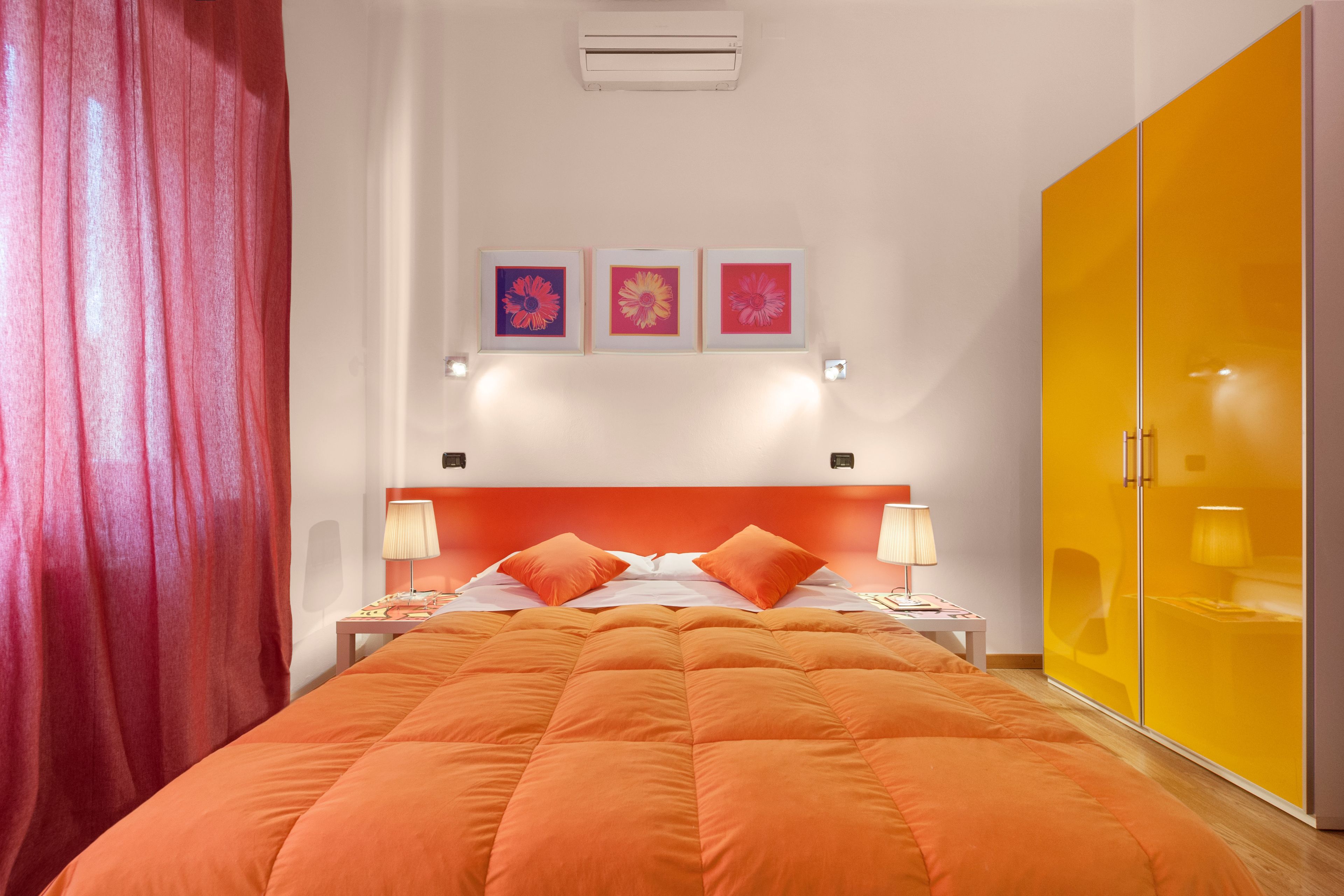 Une chambre d’hôtel avec un grand lit, une armoire et trois tableaux encadrés accrochés au mur.