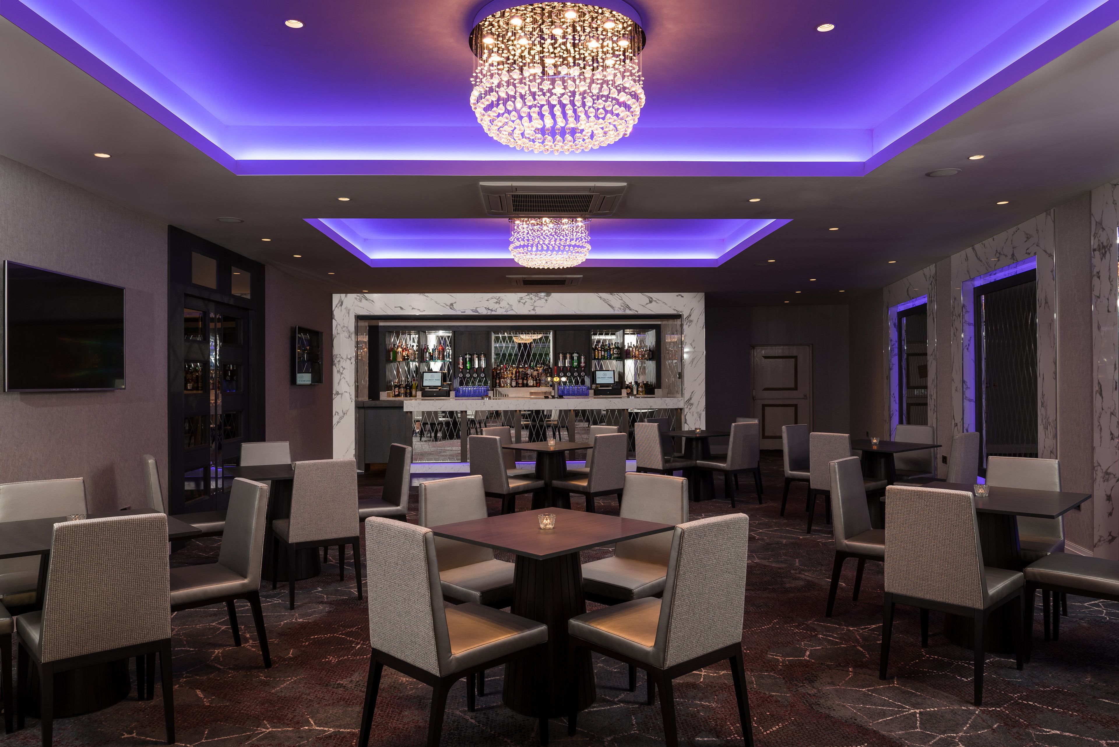 Um restaurante com área de bar, várias mesas e cadeiras.