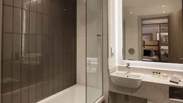 A modern bathroom with a glass-enclosed shower, a white sink, and a vanity with toiletries.