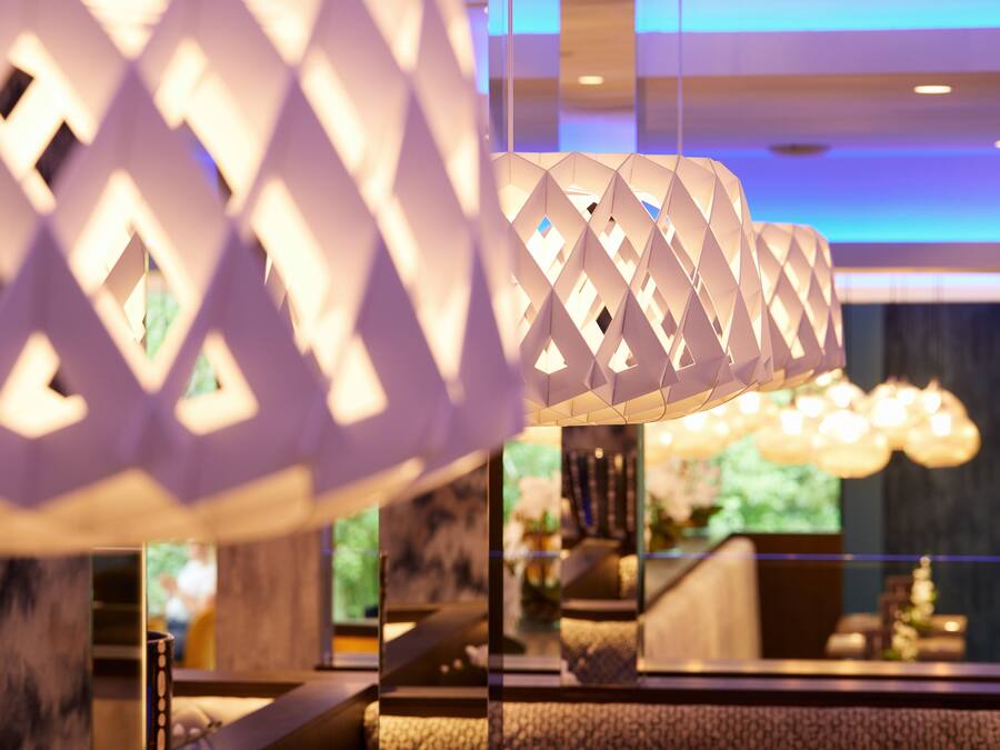 Un intérieur moderne agrémenté de lampes aux motifs géométriques et d’une colonne en marbre.