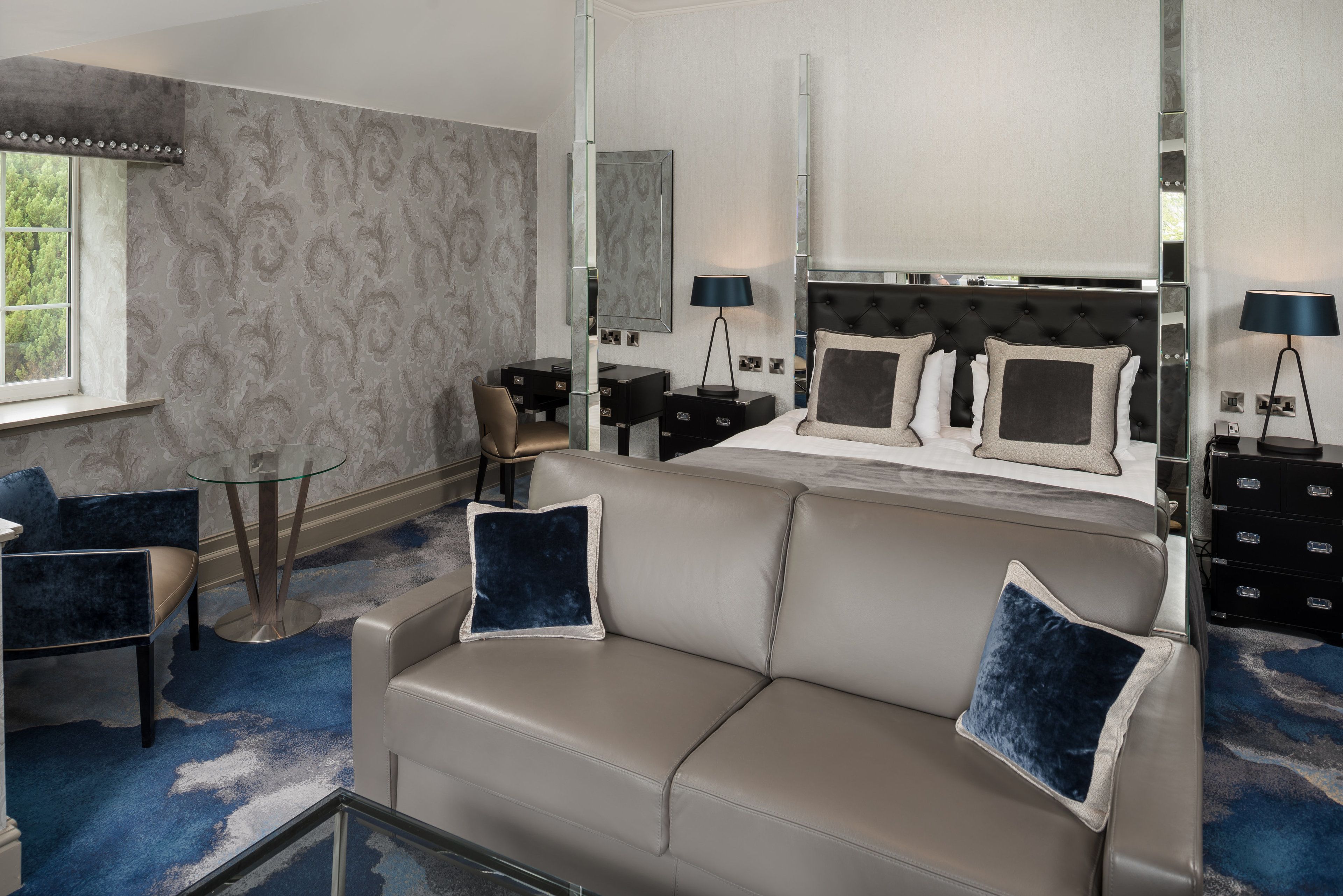A hotel room with a bed, a sofa, a desk, and a chair.