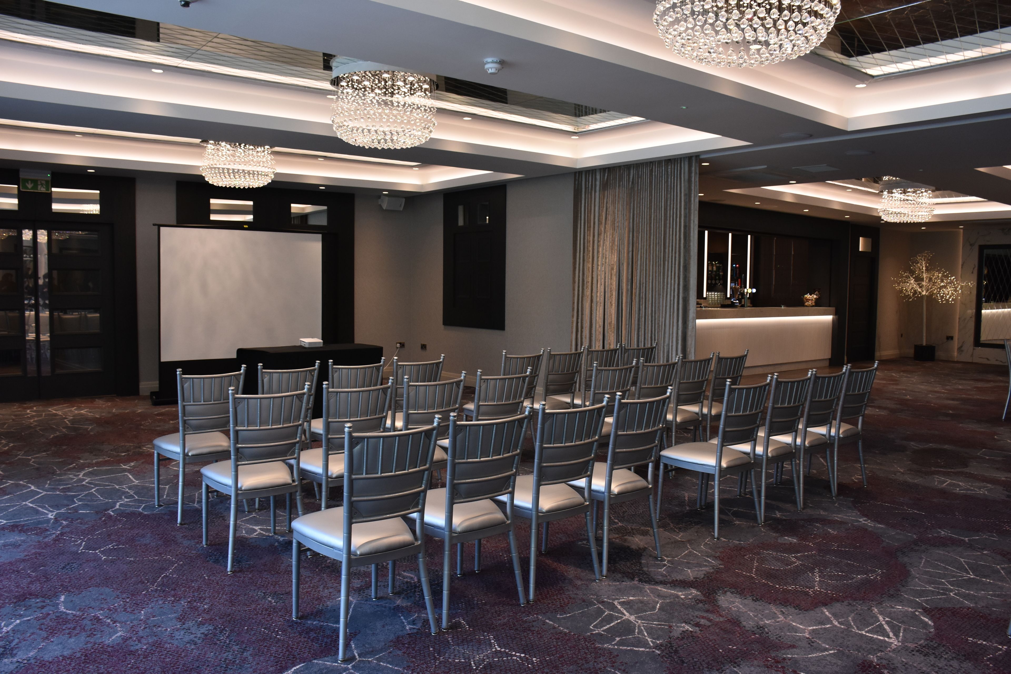 A conference room with rows of chairs, a projector screen, and a reception desk.