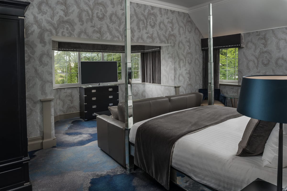 A bedroom with a bed, a TV, a dresser, and a window.