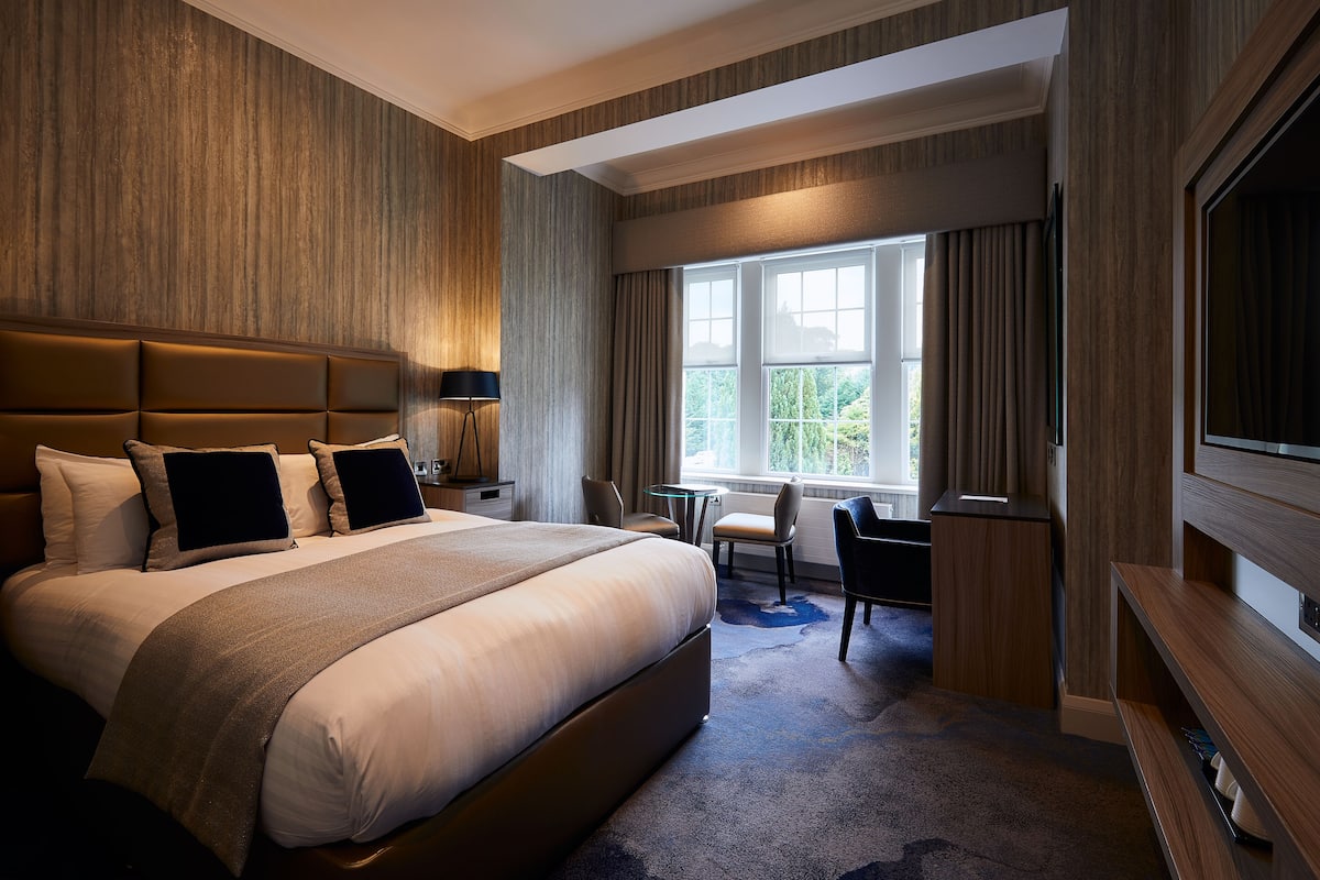 A hotel room with a large bed, a desk, and a TV.