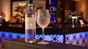 Una botella de vino Trulli y una copa de vino blanco sobre una barra.