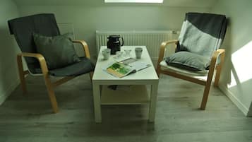 Una habitación pequeña con dos sillas de madera, una mesa blanca y una ventana.