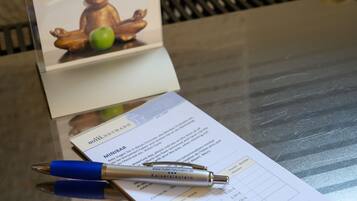 A hotel receipt with a pen on top, a bear statue, and a green apple.