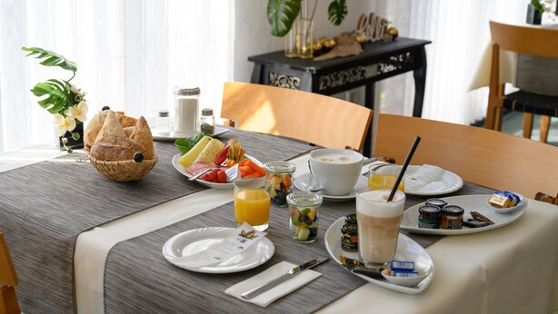 Ett frukostbord dukat med bröd, frukt, juice och kaffe.