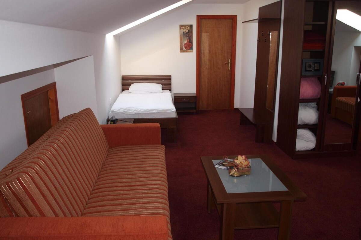 Ein Hotelzimmer mit Bett, Sofa, Tisch, Kleiderschrank und einem Gemälde an der Wand.