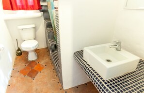 Une salle de bain avec des toilettes, un lavabo et un sol carrelé.