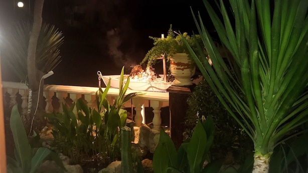 A nighttime outdoor dining area with a table set for two, surrounded by tropical plants and a decorative centerpiece. - Hostal Al-Andalus (La Guijarrosa)