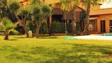 A pool area with a clear view of the pool, surrounded by a well-maintained lawn and trees.