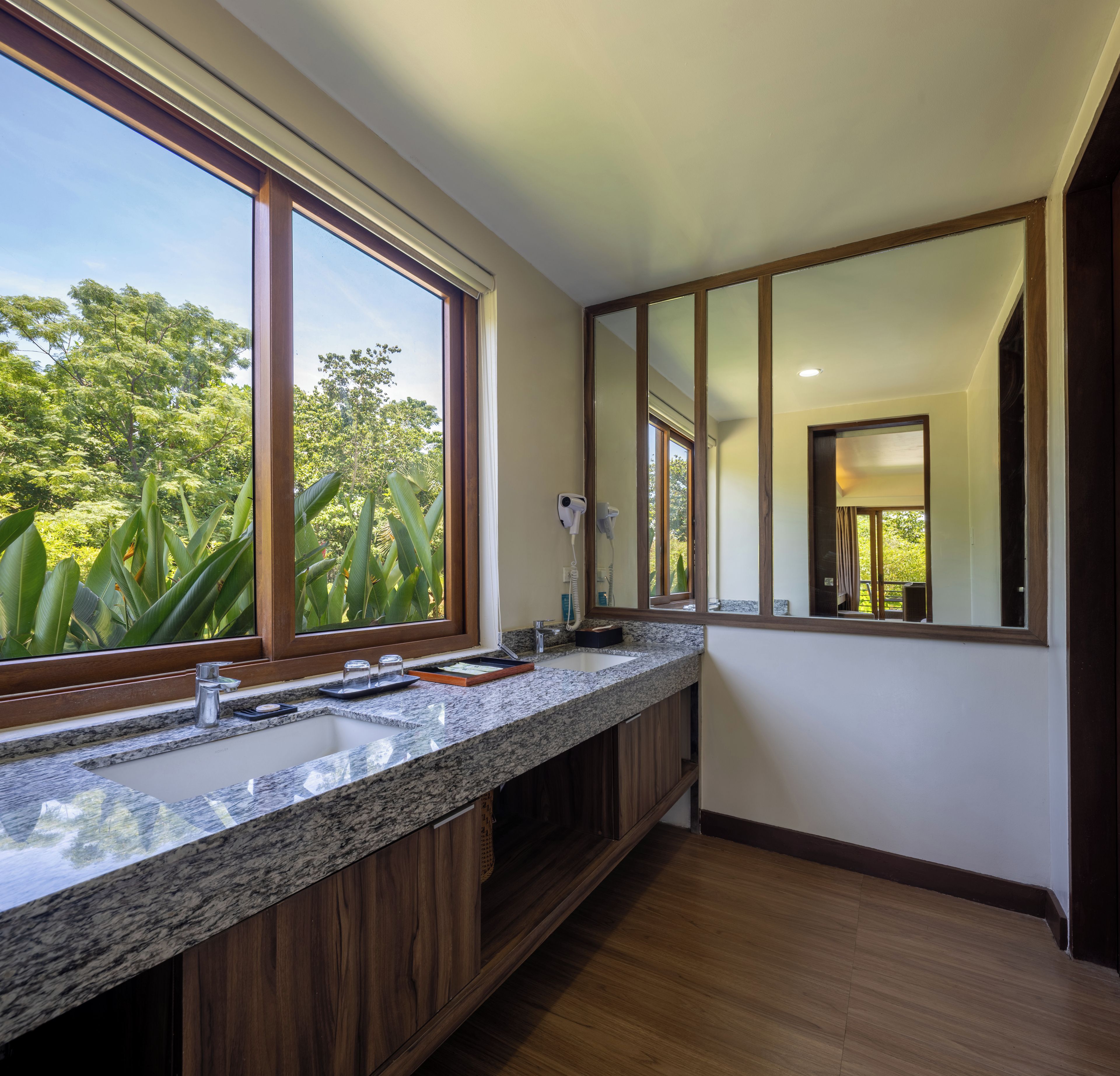 A bathroom with a large window, a sink, and a mirror.