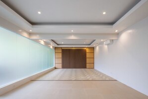 Un pasillo con suelo de baldosas claras, revestimiento de paneles de madera e iluminación empotrada en el techo.