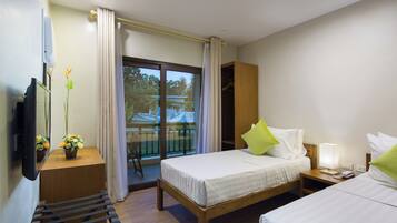A hotel room with a bed, bedside table, lamp, and a TV mounted on the wall.