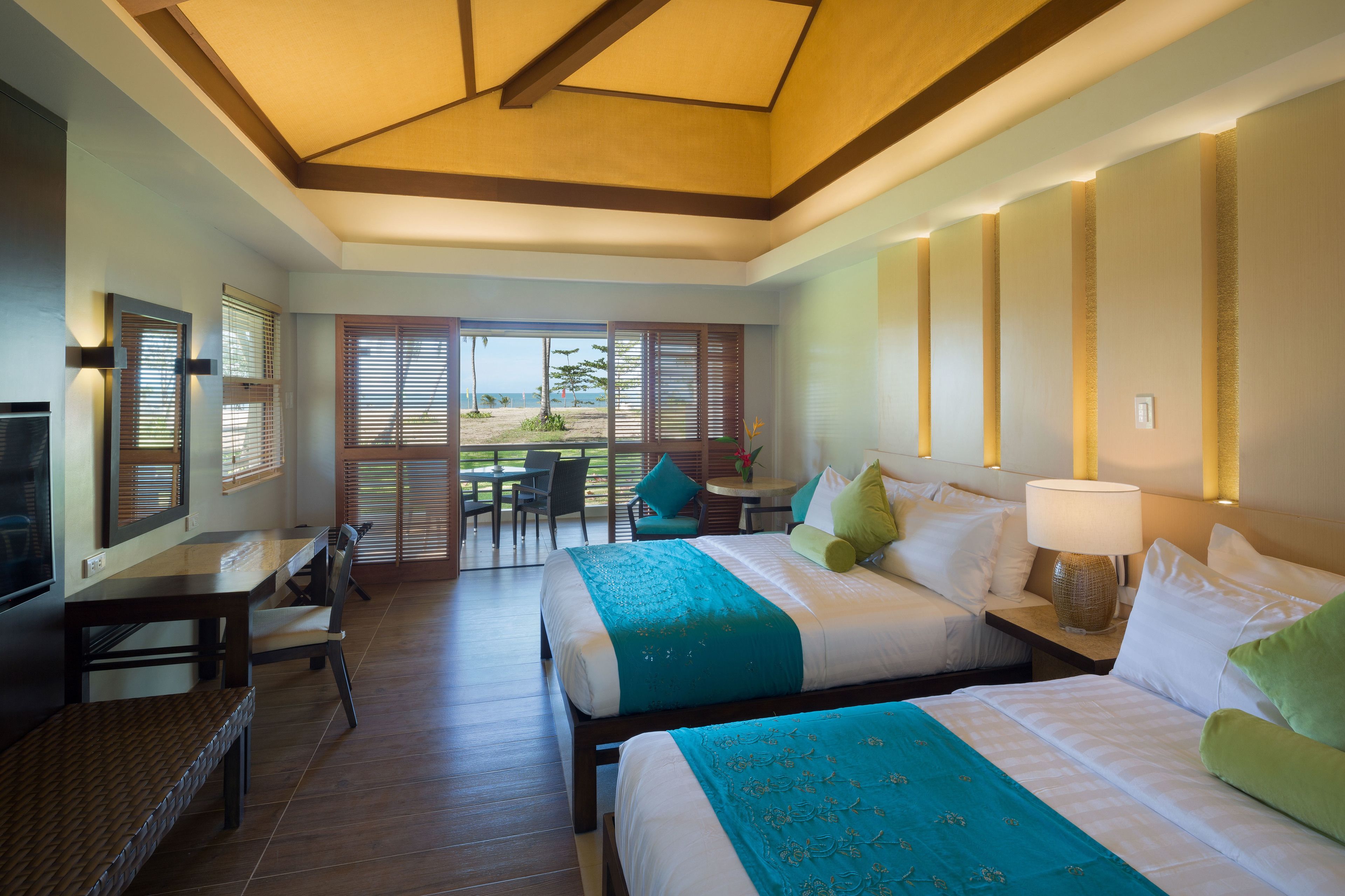 Une chambre d’hôtel avec deux lits, un bureau et vue sur la plage.