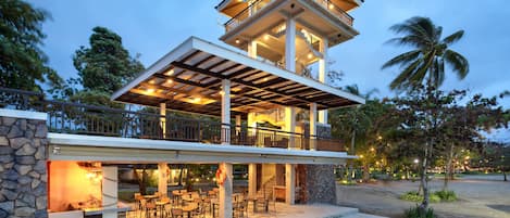A multi-story building with outdoor seating and a covered patio area.