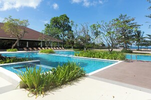 Una piscina al aire libre, sombrillas, sillones reclinables de piscina