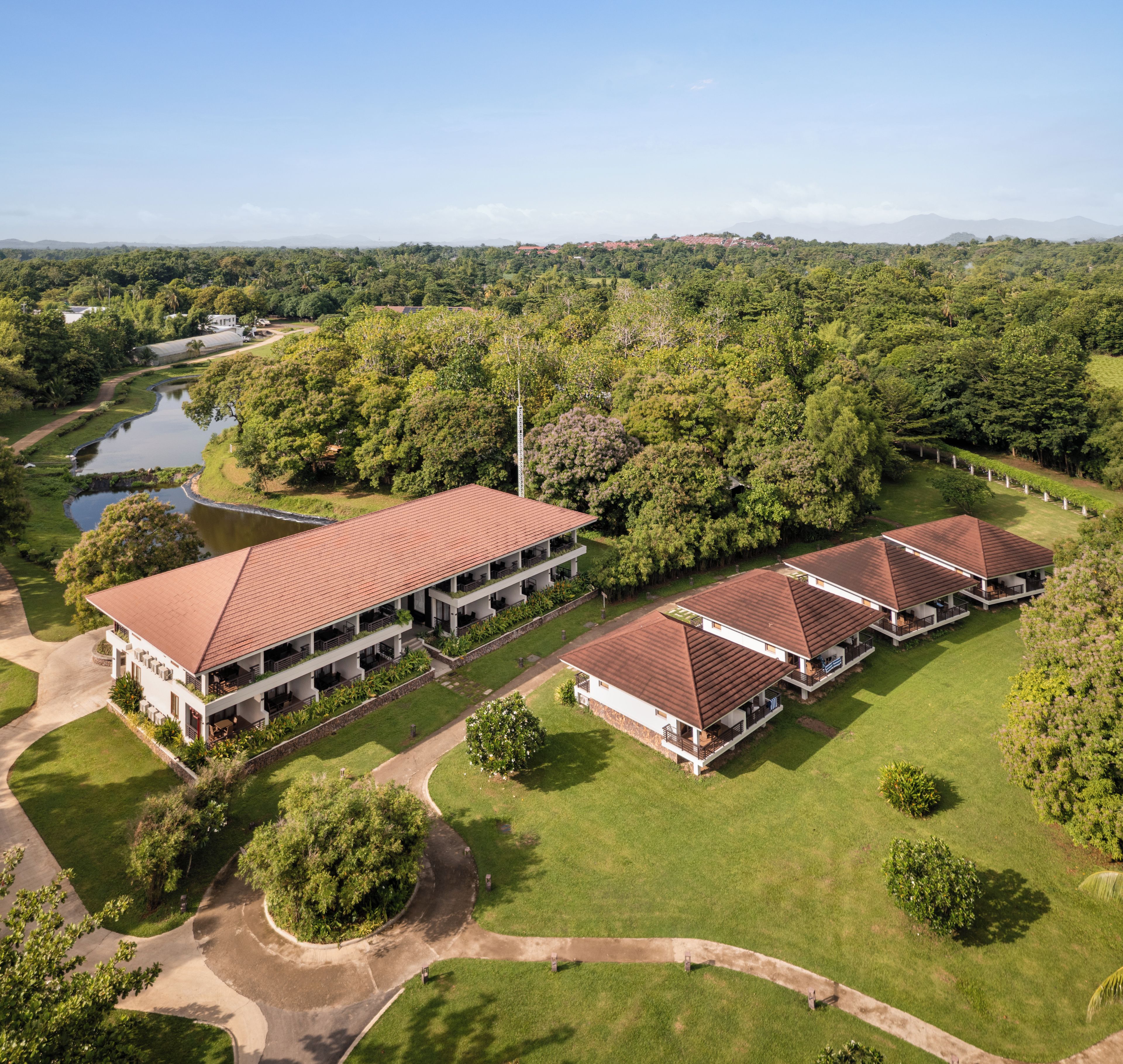 A large, modern hotel with multiple buildings, a central courtyard, and a surrounding lush landscape.