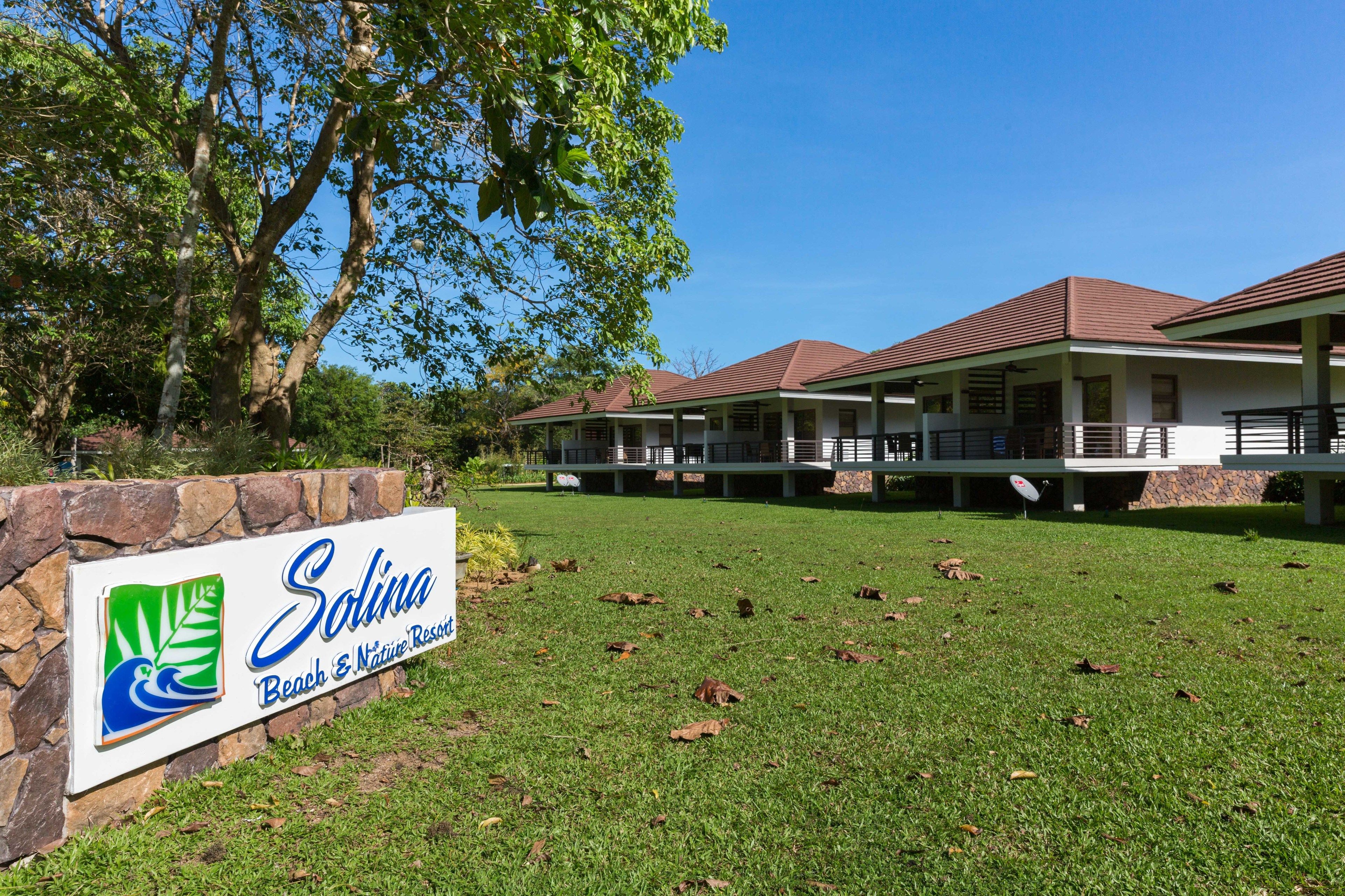A sign for 'Solina Beach & Nature Resort' with a stone wall and grass in front.