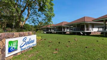 A sign for 'Solina Beach & Nature Resort' with a stone wall and grass in front.