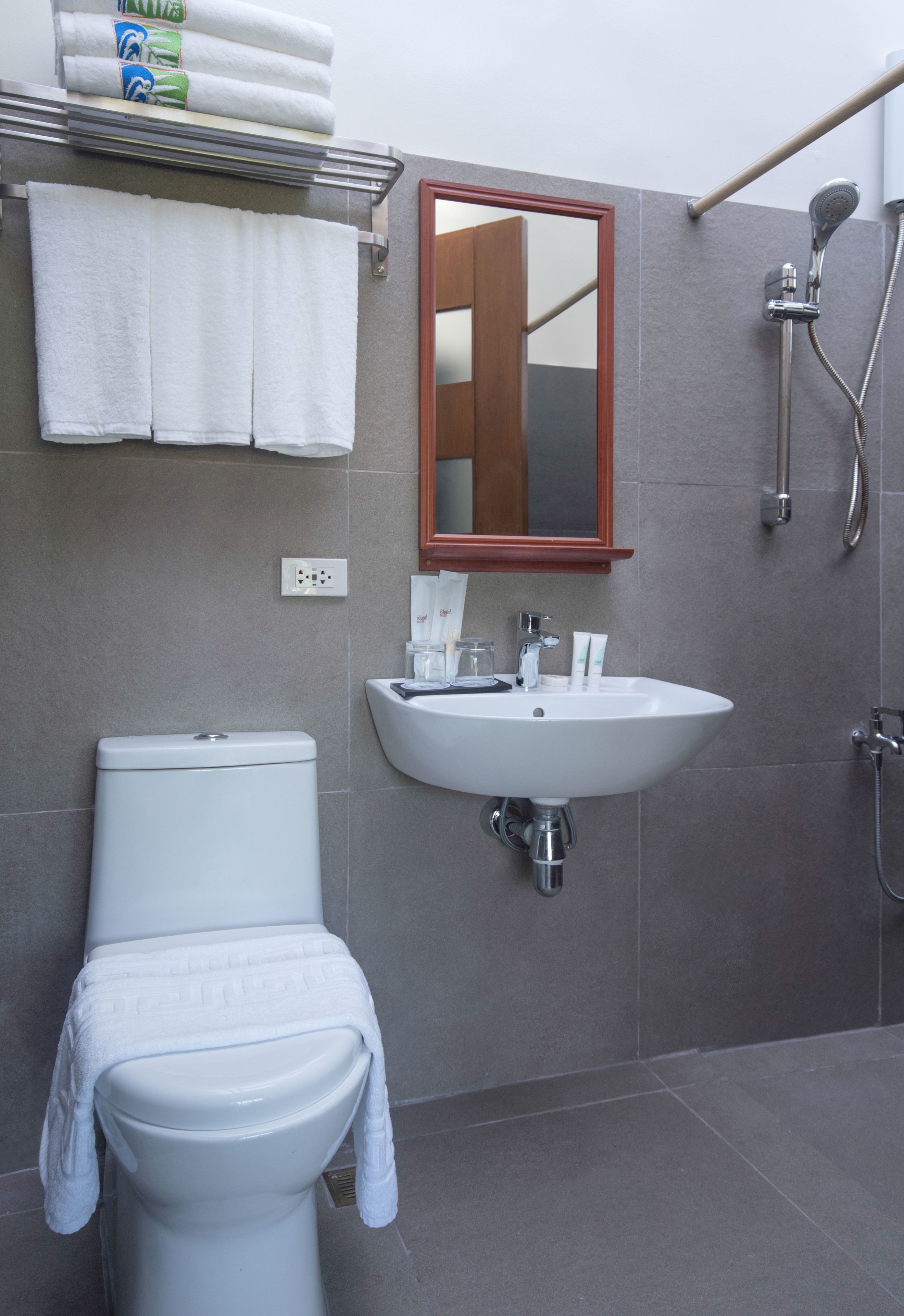 A bathroom with a toilet, sink, mirror, shower, and towel rack.