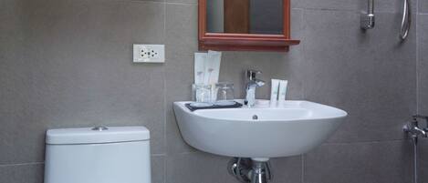 A bathroom with a toilet, sink, mirror, shower, and towel rack.