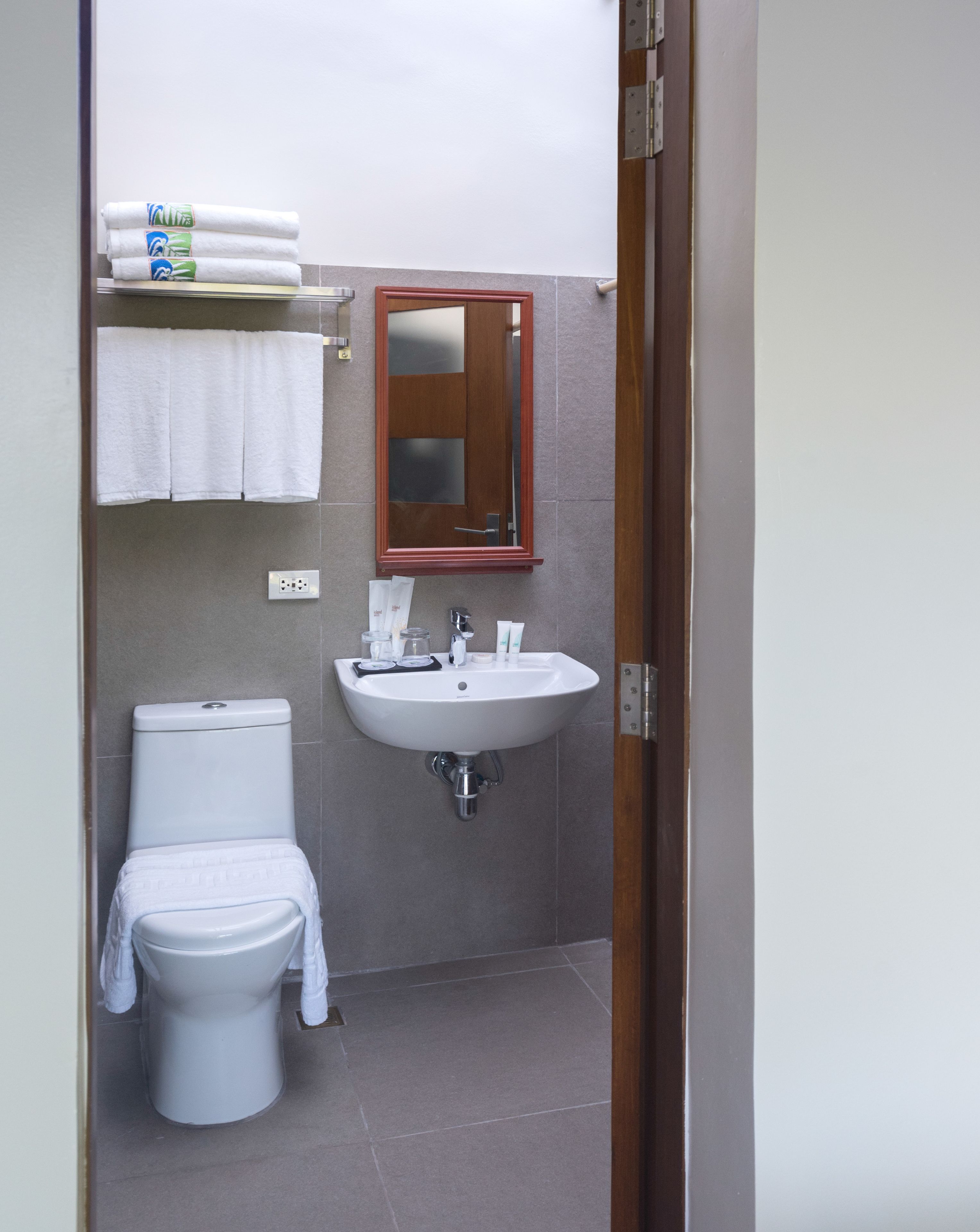 A compact bathroom with a toilet, sink, and mirror.