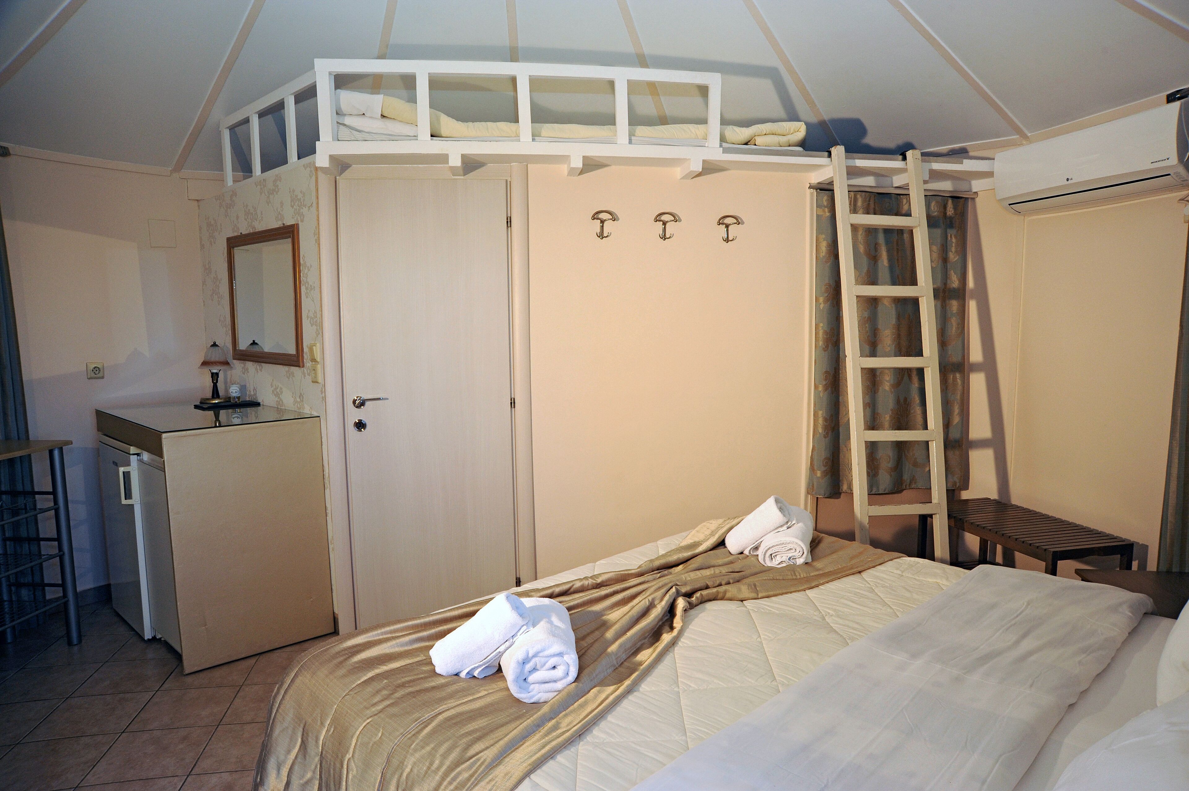 Ein Schlafzimmer mit Etagenbett, Schreibtisch, Spiegel und Kleiderschrank.