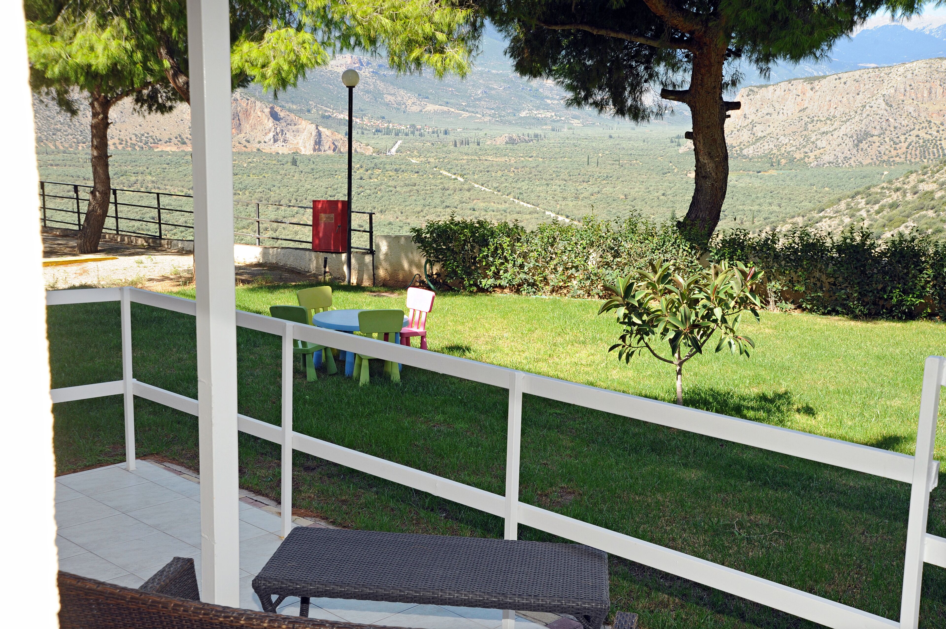 A covered patio with a white railing, a bench, and a table.
