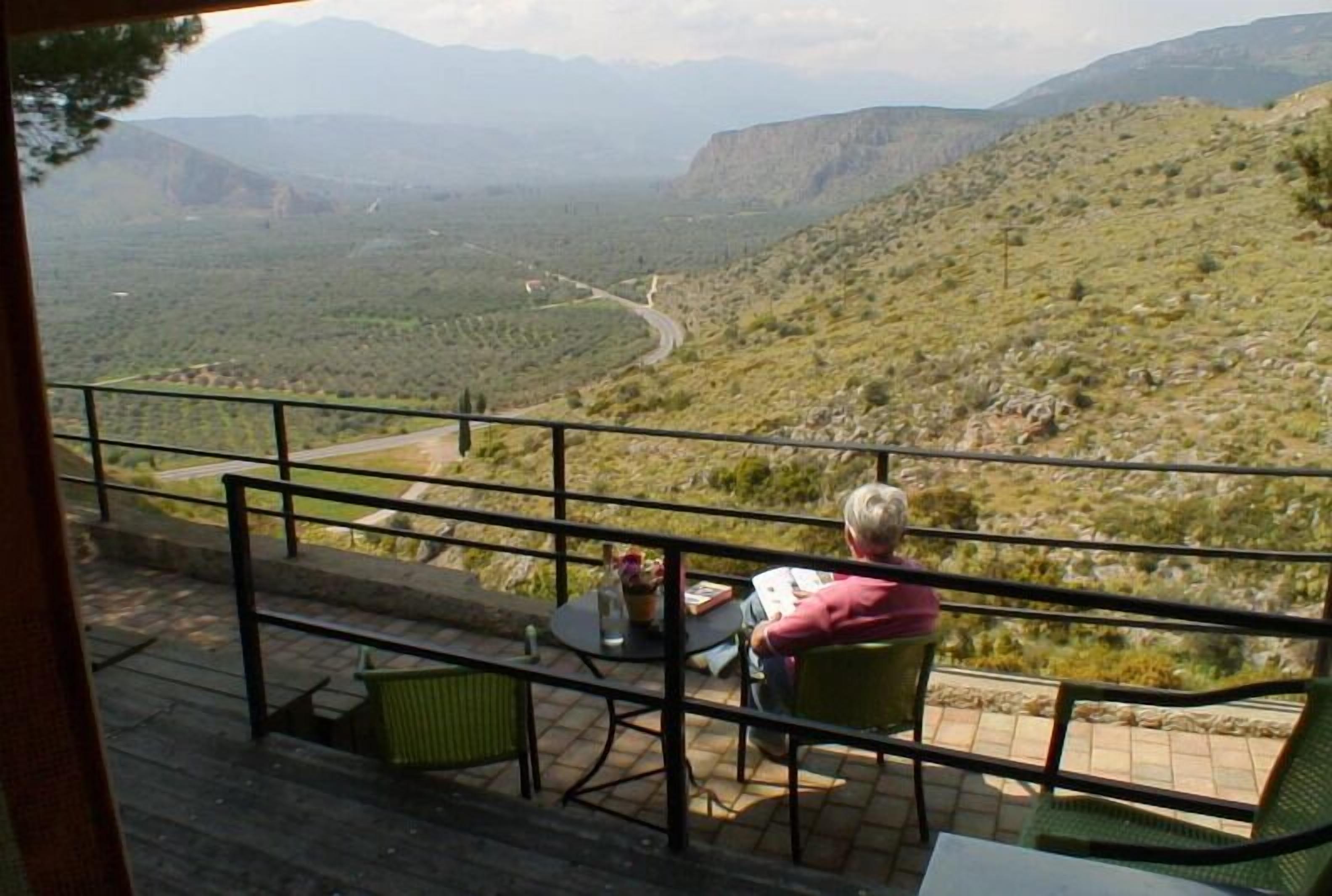 A terrace with a table and chairs overlooking a mountainous landscape.