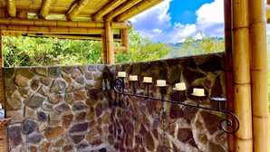 Un mur en pierre avec un banc en pierre et un porte-bougie en métal contenant des bougies.