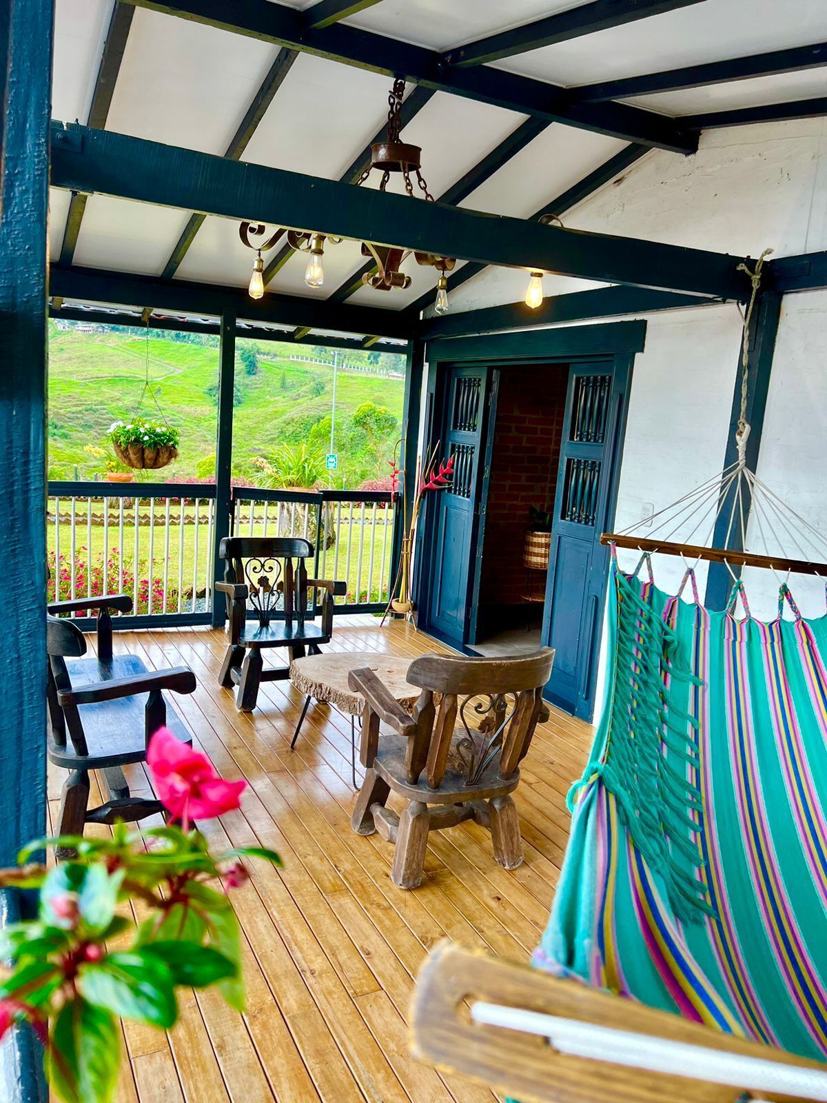 A wooden deck with outdoor seating, a hammock, and a view of greenery.