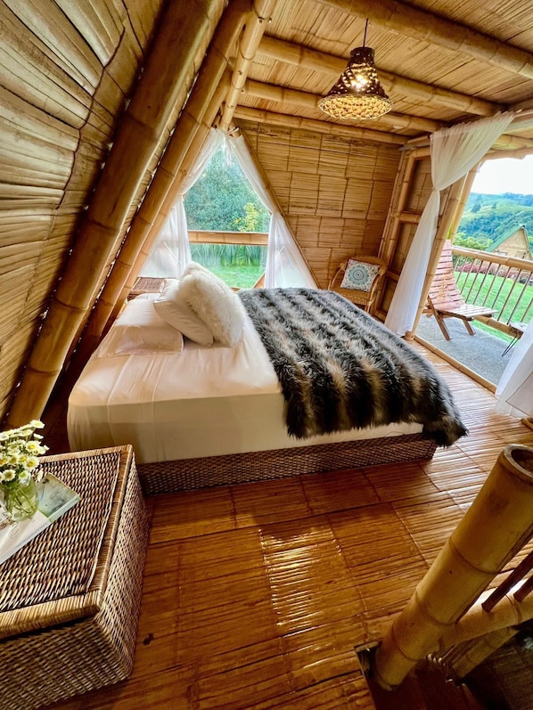 Una habitación acogedora con paneles de madera, una cama, una mesita de mimbre y vistas al exterior.